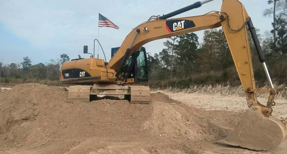 CAT excavator digging at a sand pit with an American flag