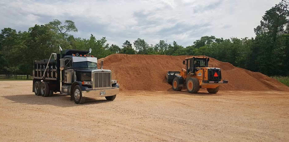 Wheel loader at a sand stockpile next to a Nick's Peterbilt